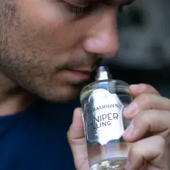 Mężczyzna wącha butelkę wody toaletowej Penhaligon's Juniper Sling.