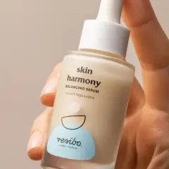 Dłoń trzyma buteleczkę serum Resibo z alantoiną, które koi i nawilża skórę.