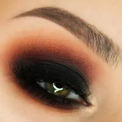 Oko z perfekcyjnym makijażem w stylu smokey eyes, podkreślone czernią i brązem.