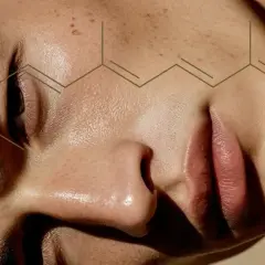 Zbliżenie na twarz z nałożonym wzorem chemicznym. Witamina A, znana jako retinol, odżywia skórę.