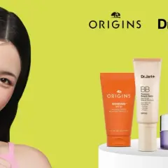 Młoda kobieta aplikuje na twarz kosmetyk z filtrem SPF. Obok niej produkty Origins, Dr.Jart+ i Clinique, pomagające wybrać jaki SPF do twarzy będzie najlepszy.