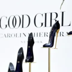 Eleganckie szpilki Good Girl od Carolina Herrera, prezentowane na złotych stojakach, symbolizują odwagę i styl.