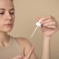 Kobieta aplikuje serum z ceramidami i peptydami na dłoń.