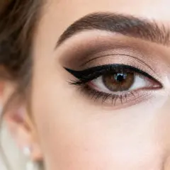 Oko kobiety o śniadej karnacji z perfekcyjną kreską eyelinera i brązowymi cieniami.