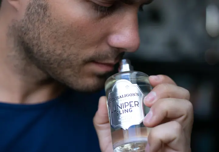 Mężczyzna wącha butelkę wody toaletowej Penhaligon's Juniper Sling.