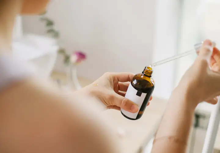Kobieta aplikuje serum z niacynamidem na dłoń. Bezpieczny wybór dla skóry w ciąży.