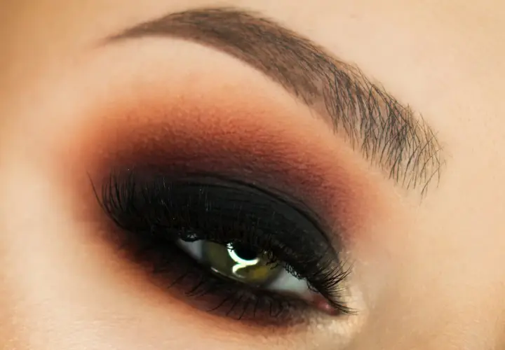 Oko z perfekcyjnym makijażem w stylu smokey eyes, podkreślone czernią i brązem.