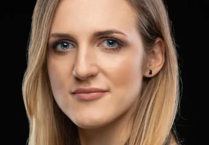 Portret kobiety z niebieskimi oczami i blond włosami, emanującej pewnością siebie i **body positive**.