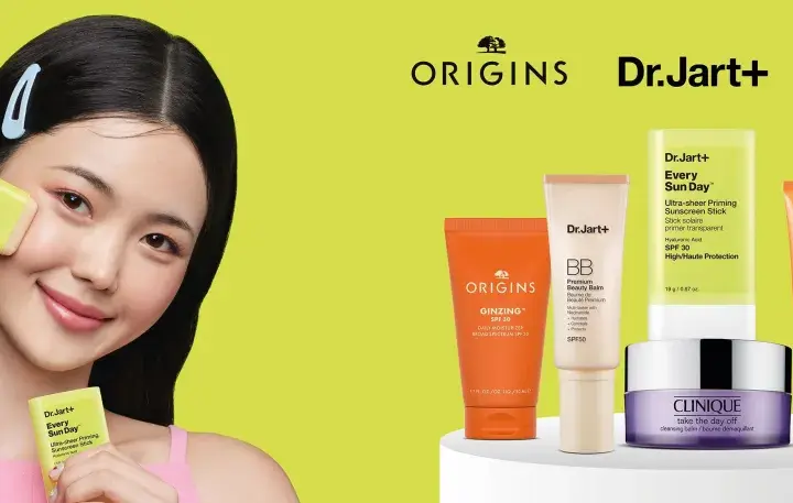 Młoda kobieta aplikuje na twarz kosmetyk z filtrem SPF. Obok niej produkty Origins, Dr.Jart+ i Clinique, pomagające wybrać jaki SPF do twarzy będzie najlepszy.