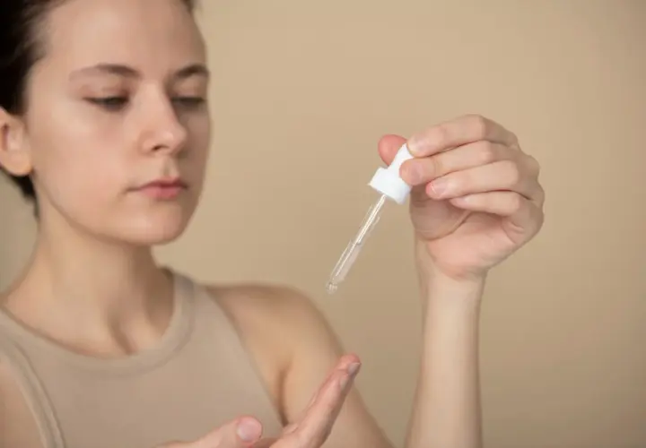 Kobieta aplikuje serum z ceramidami i peptydami na dłoń.