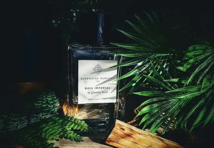 Elegancka butelka perfum Bois Impérial otoczona bujną zielenią i kawałkiem drewna, przywołująca na myśl egzotyczny zapach akigalawood.