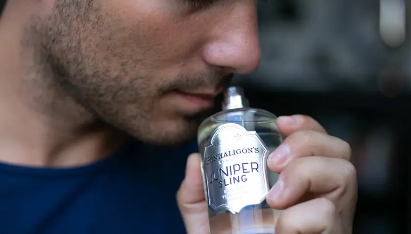 Mężczyzna wącha butelkę wody toaletowej Penhaligon's Juniper Sling.