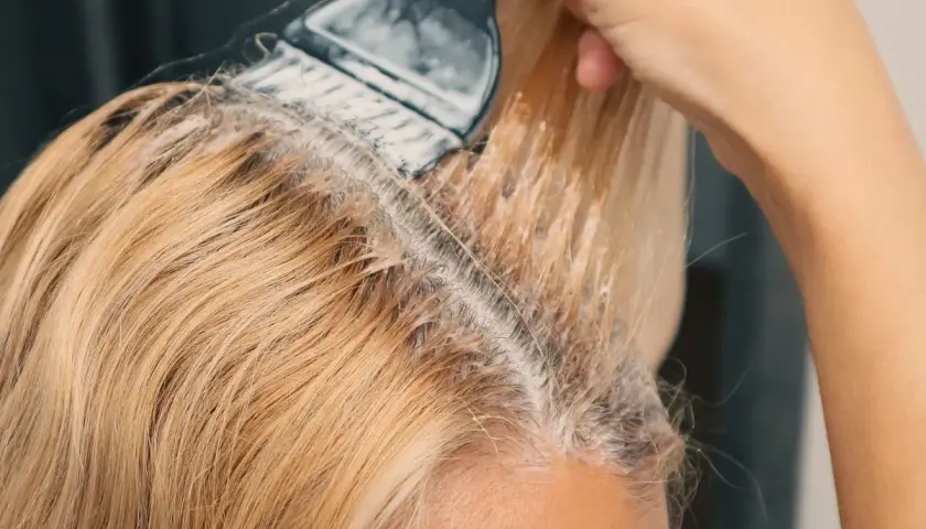 Nakładanie najmniej szkodliwego rozjaśniacza do włosów na blond pasma. Delikatne rozjaśnianie dla pięknego efektu.