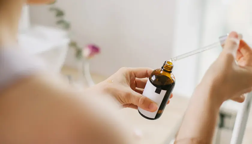 Kobieta aplikuje serum z niacynamidem na dłoń. Bezpieczny wybór dla skóry w ciąży.