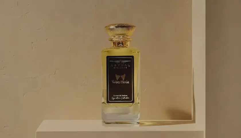 Elegancka butelka perfum "Won Hedia" z nutami kadzidła, w złotym korku, na tle teksturowanej ściany.