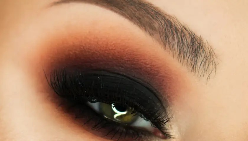 Oko z perfekcyjnym makijażem w stylu smokey eyes, podkreślone czernią i brązem.