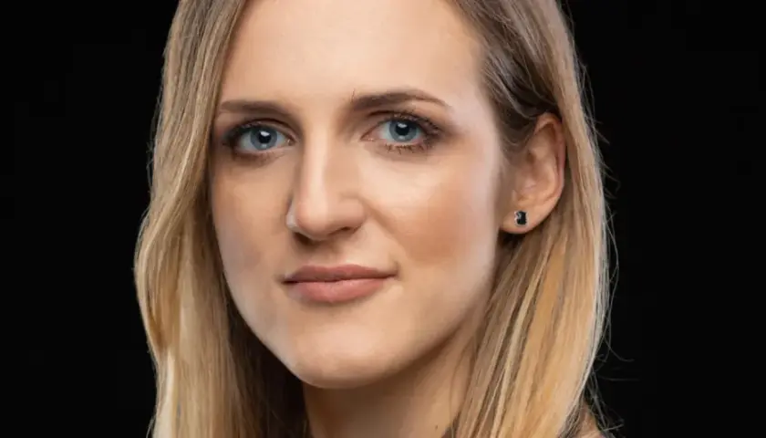 Portret kobiety z niebieskimi oczami i blond włosami, emanującej pewnością siebie i **body positive**.