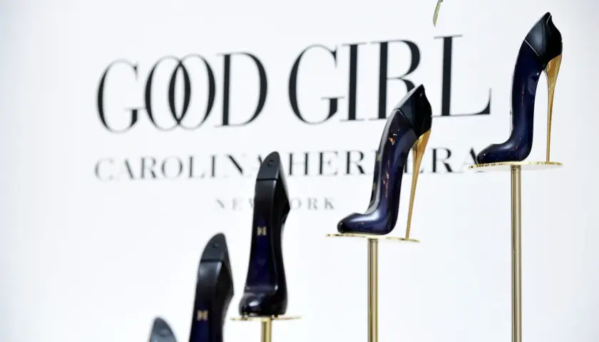 Eleganckie szpilki Good Girl od Carolina Herrera, prezentowane na złotych stojakach, symbolizują odwagę i styl.