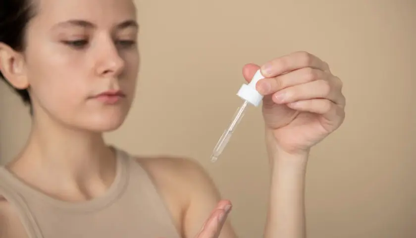 Kobieta aplikuje serum z ceramidami i peptydami na dłoń.
