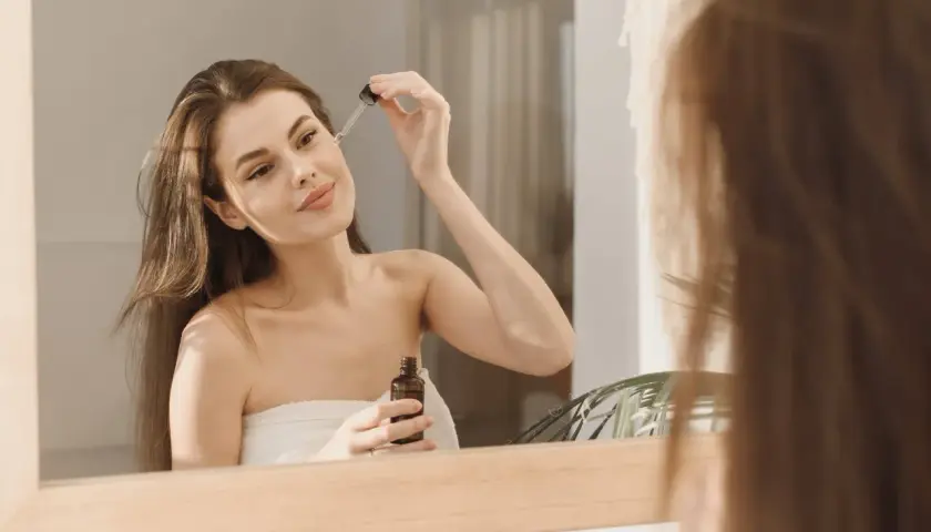 Kwas azelainowy z czym nie łączyć? Kobieta aplikuje serum na twarz, dbając o cerę.