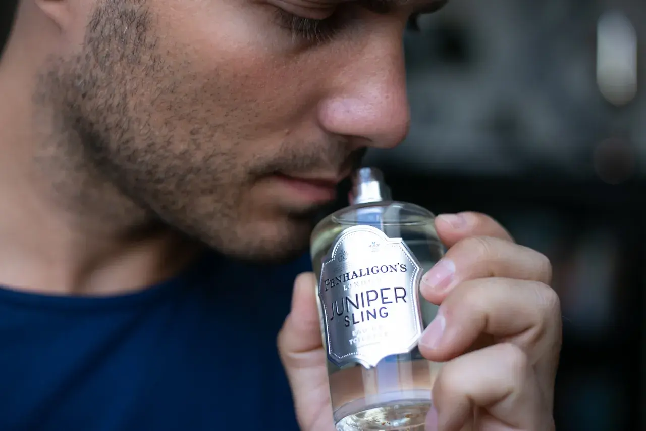 Mężczyzna wącha butelkę wody toaletowej Penhaligon's Juniper Sling.
