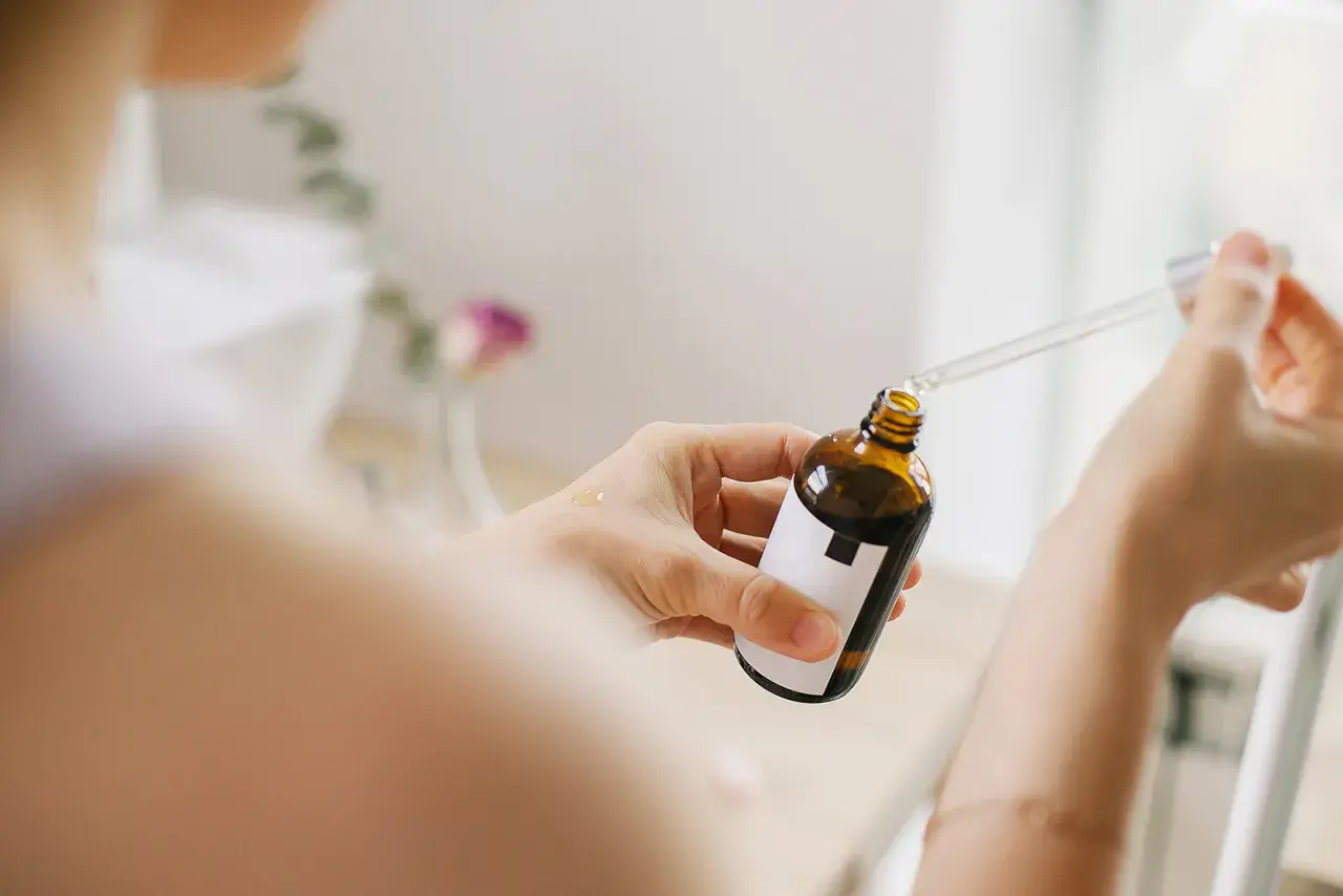 Kobieta aplikuje serum z niacynamidem na dłoń. Bezpieczny wybór dla skóry w ciąży.