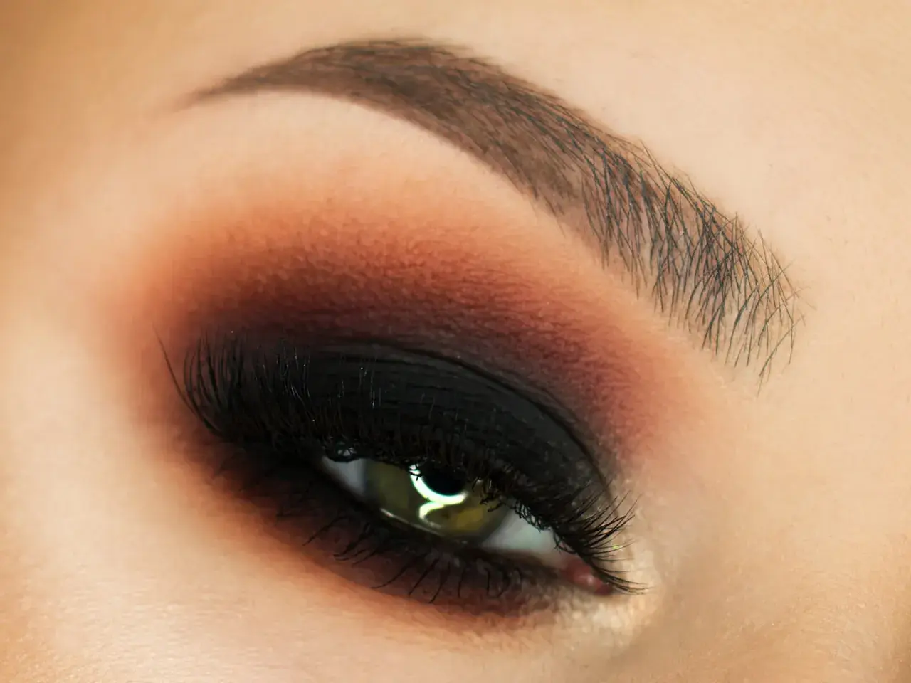 Oko z perfekcyjnym makijażem w stylu smokey eyes, podkreślone czernią i brązem.