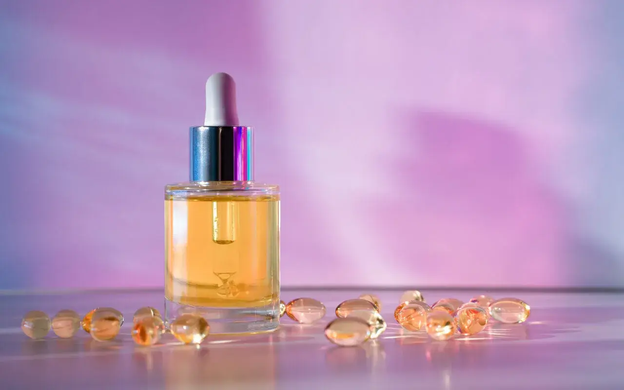 Szklana buteleczka z serum i kapsułki na fioletowym tle. Wybór między retinol czy retinal dla pięknej skóry.