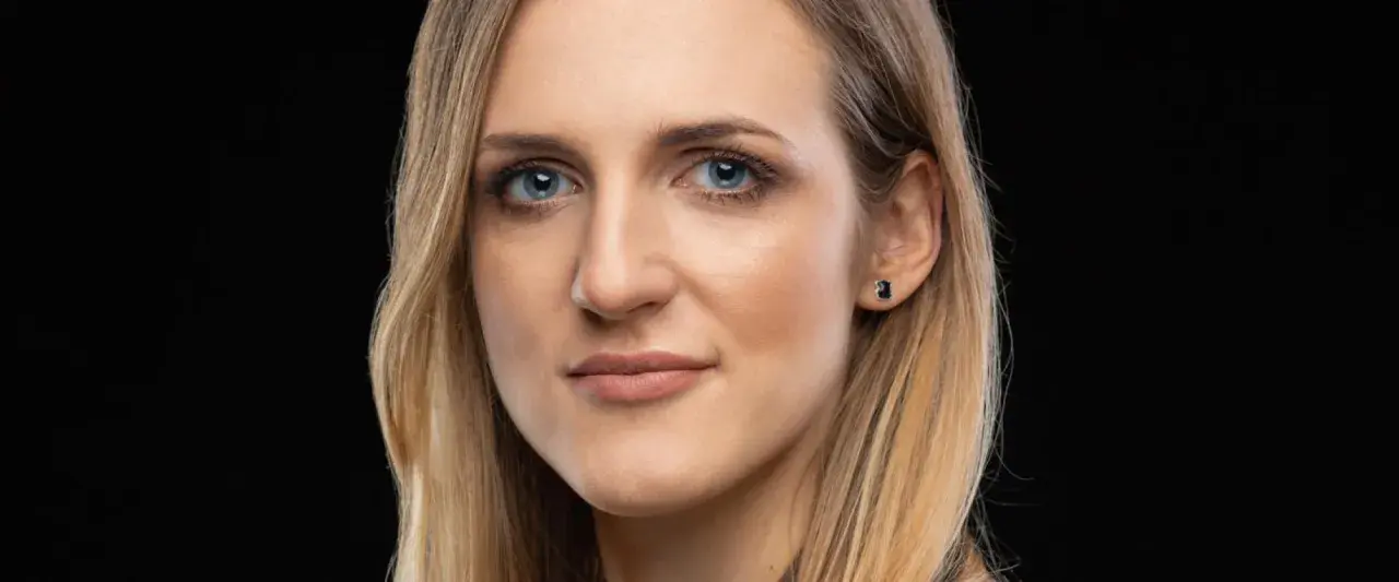 Portret kobiety z niebieskimi oczami i blond włosami, emanującej pewnością siebie i **body positive**.