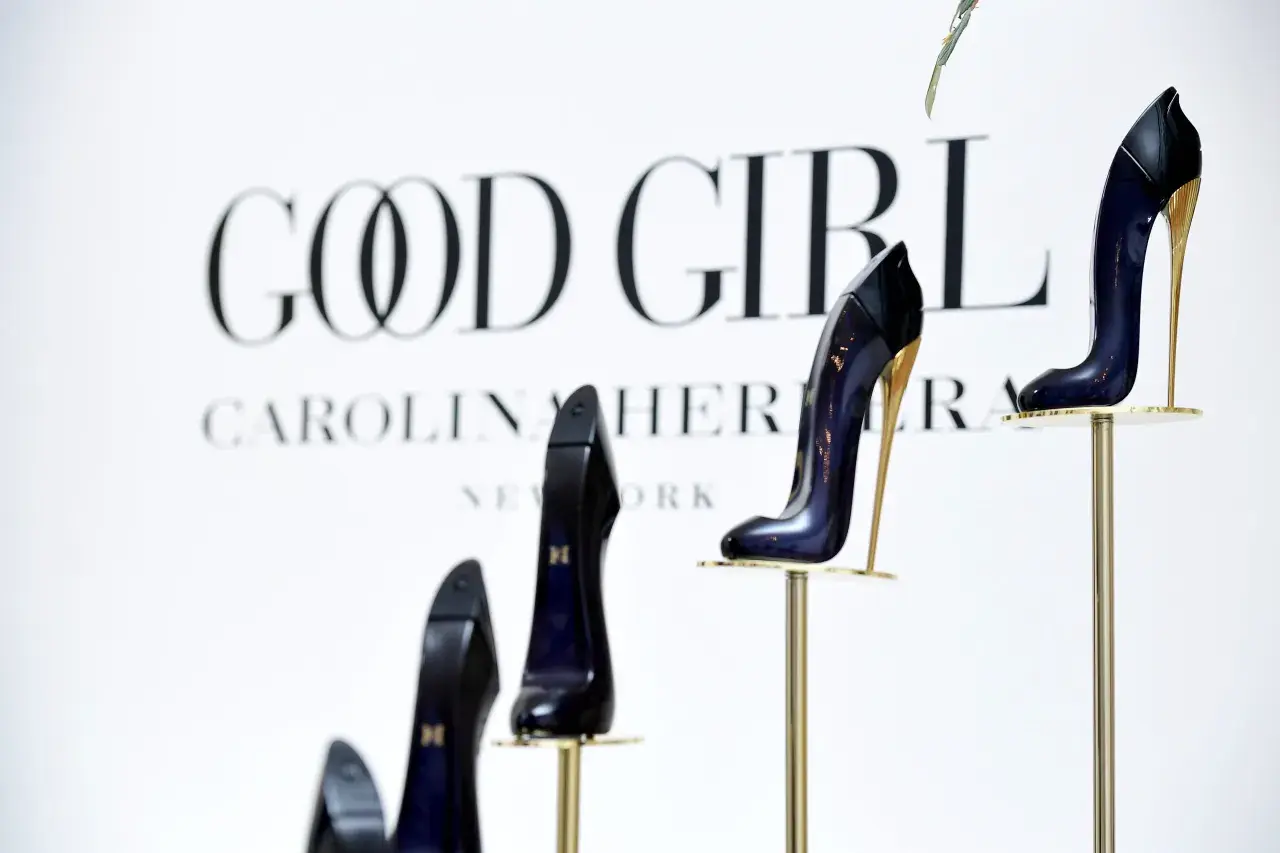 Eleganckie szpilki Good Girl od Carolina Herrera, prezentowane na złotych stojakach, symbolizują odwagę i styl.