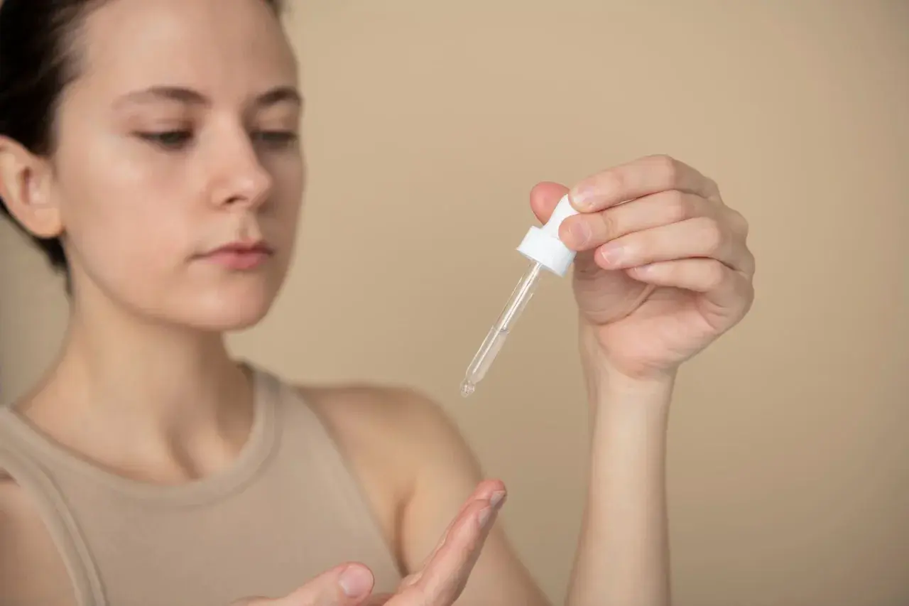 Kobieta aplikuje serum z ceramidami i peptydami na dłoń.