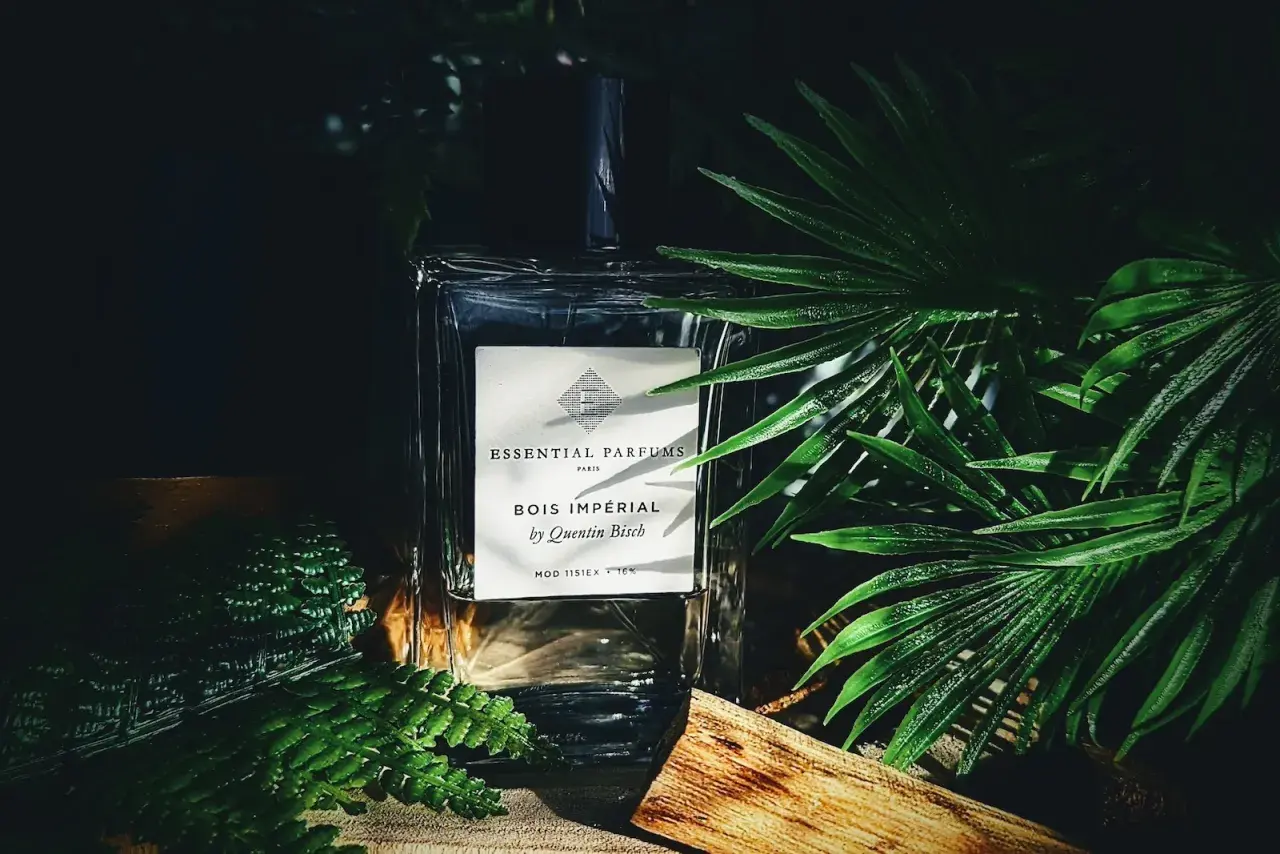Elegancka butelka perfum Bois Impérial otoczona bujną zielenią i kawałkiem drewna, przywołująca na myśl egzotyczny zapach akigalawood.