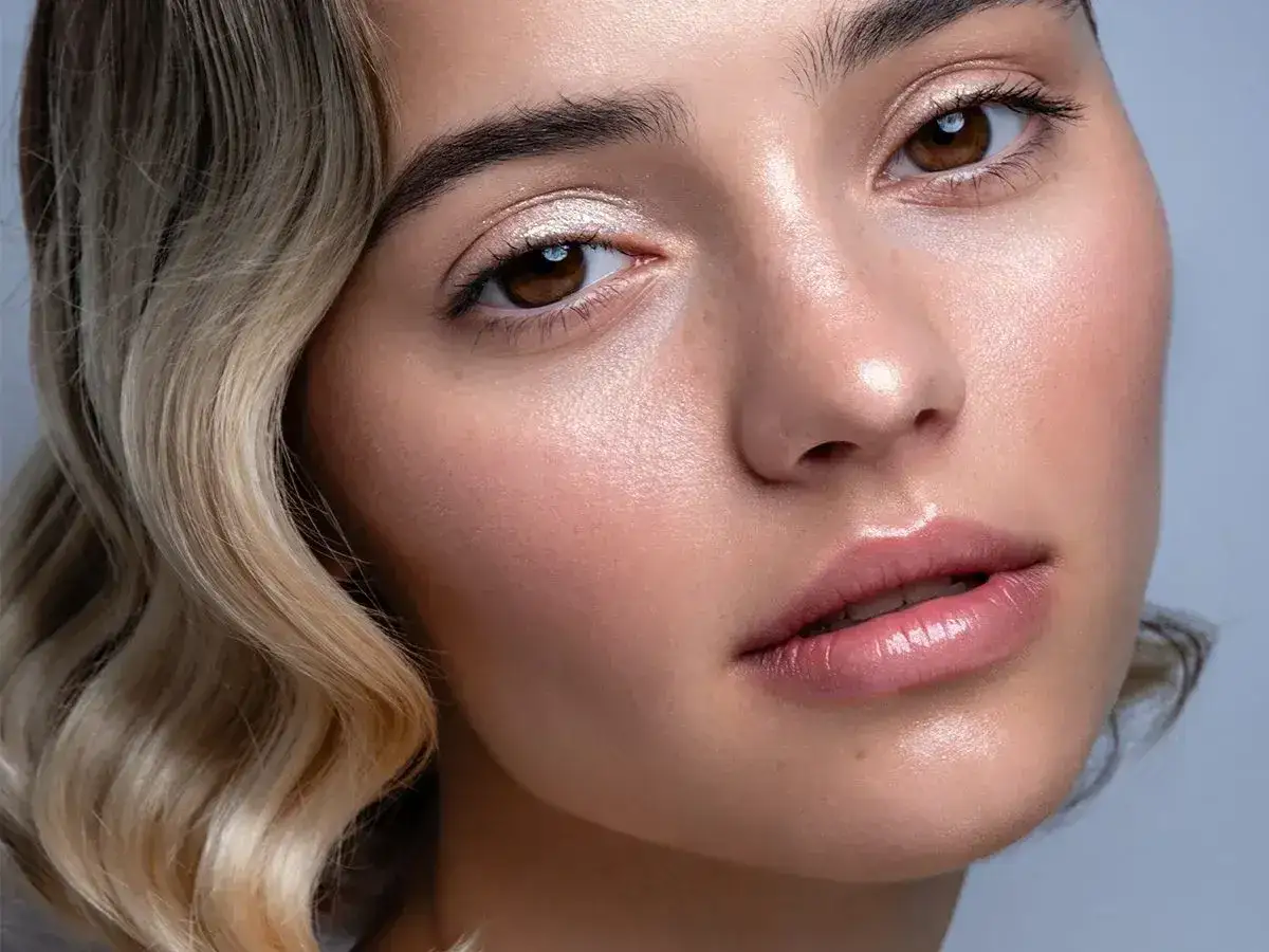 Młoda kobieta z lśniącą cerą i delikatnym makijażem, jej twarz to prawdziwy glow up.