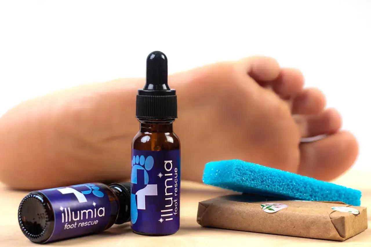 Pielęgnacja stóp z Illumia Foot Rescue. W tle ludzka stopa, a na pierwszym planie buteleczki z kroplomierzem i pumeks. Mocznik co to jest? To składnik nawilżający.