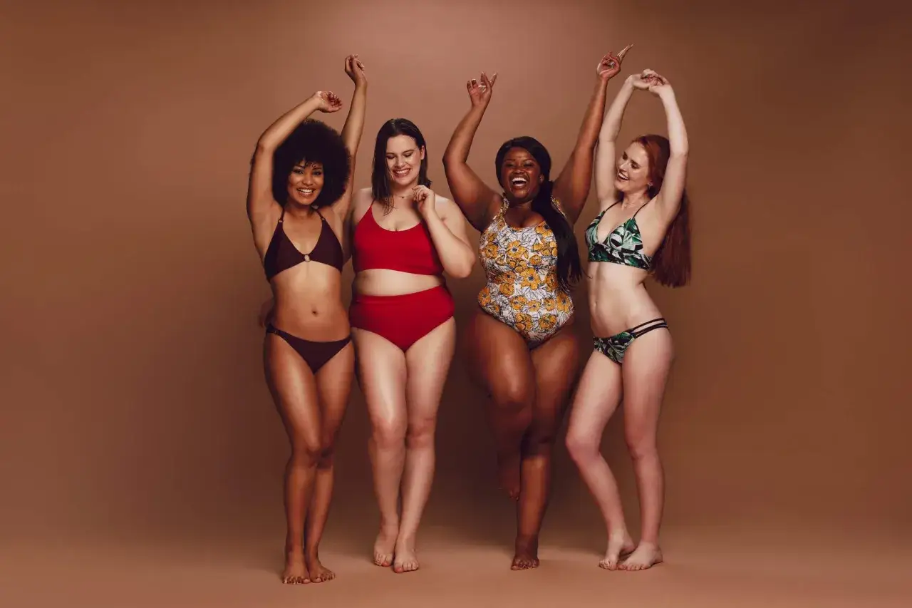 Cztery kobiety w strojach kąpielowych świętują piękno ciała. Różnorodność kształtów i rozmiarów to esencja body positive.